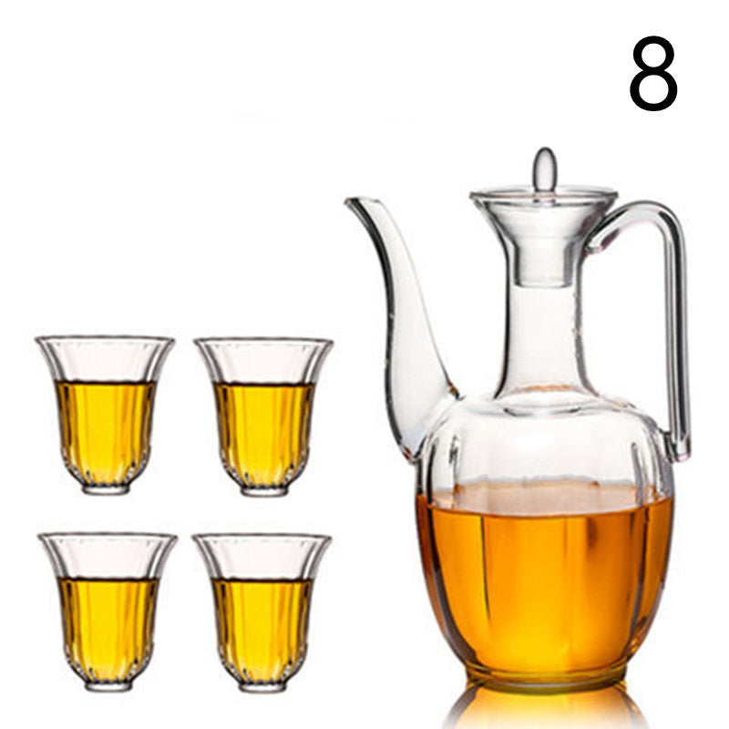 a glass pitcher with a handle and a glass cup with yellow liquid