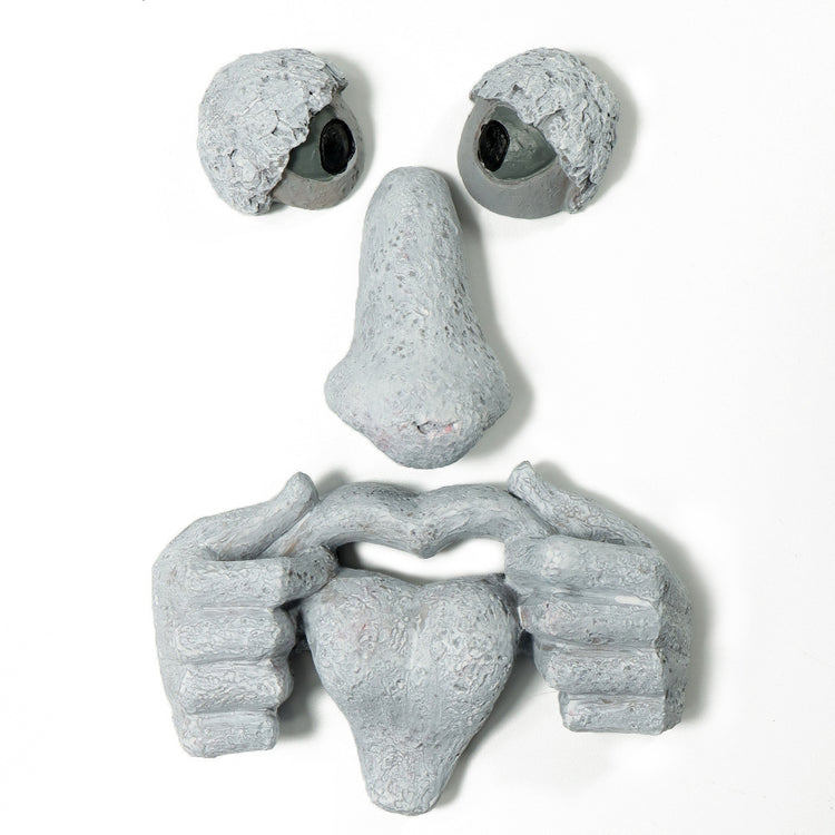 a clay face with hands and eyes