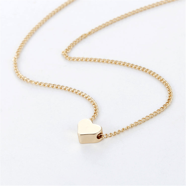 a gold heart necklace on a white surface