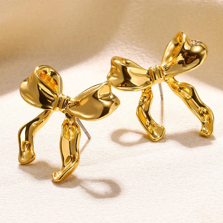 a pair of gold earrings with bows
