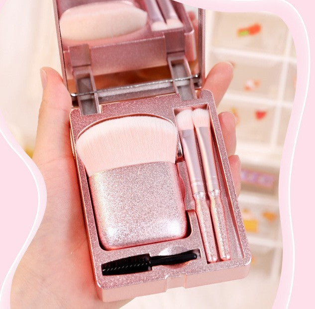 a hand holding a pink makeup set