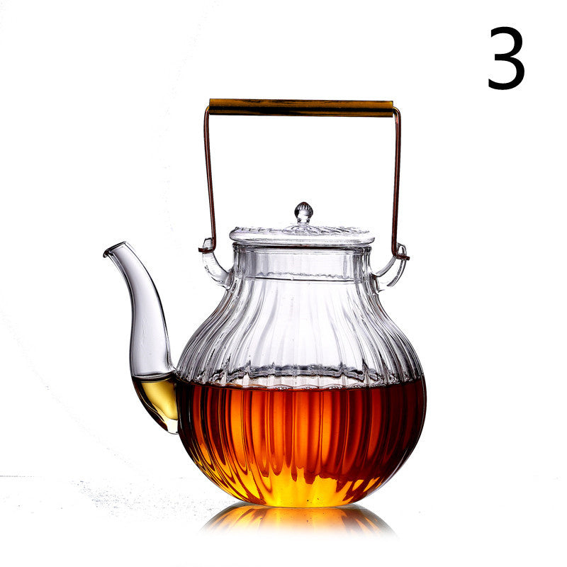a glass teapot with a handle and a brown liquid