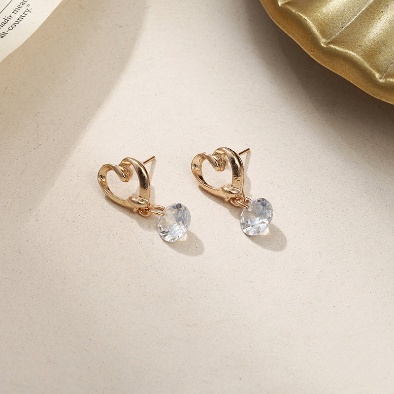 a pair of gold earrings with a heart shaped stone