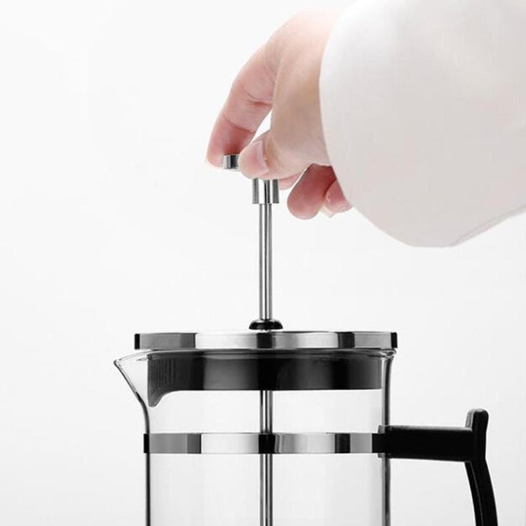 a hand holding a metal handle on a glass coffee pot