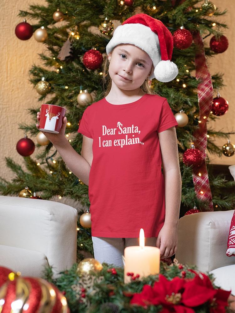 a girl in a red shirt holding a mug in front of a christmas tree