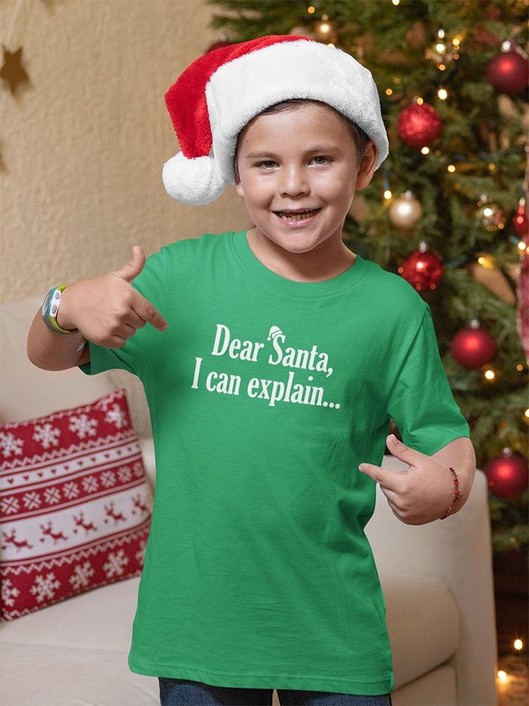 a boy wearing a santa hat pointing at his shirt