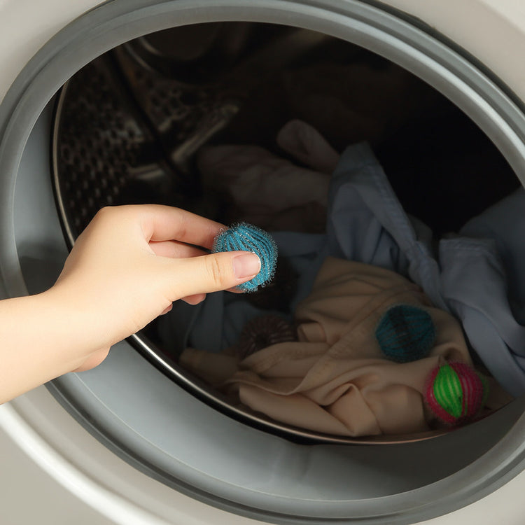 a hand holding a ball of clothes in a washing machine