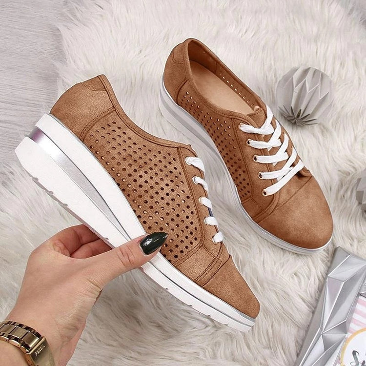 a hand holding a pair of brown shoes