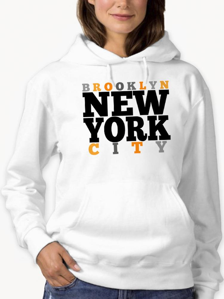 a woman wearing a white sweatshirt with black and orange text