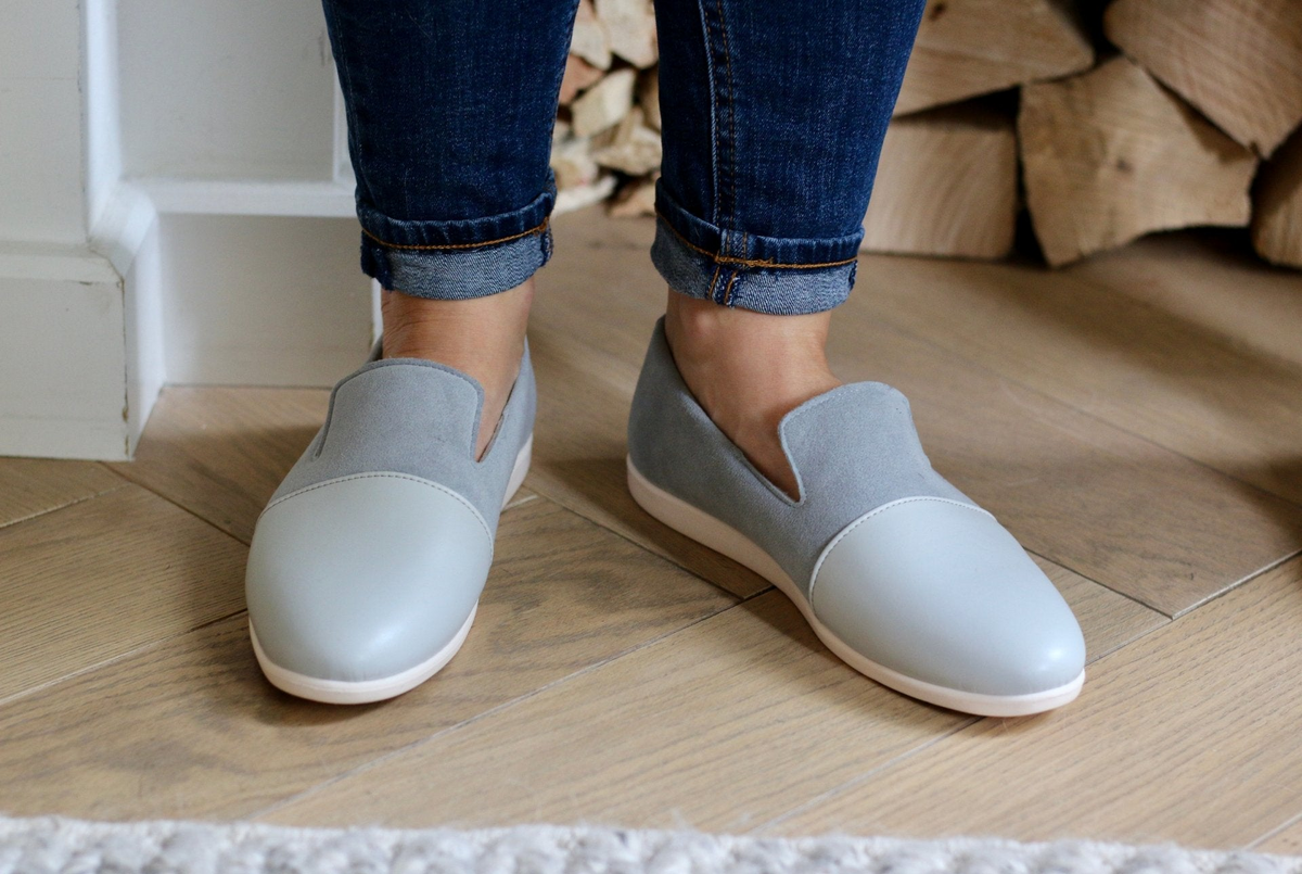 a person's feet wearing grey shoes