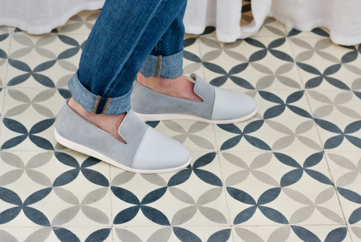 a person's legs and feet wearing jeans and slippers