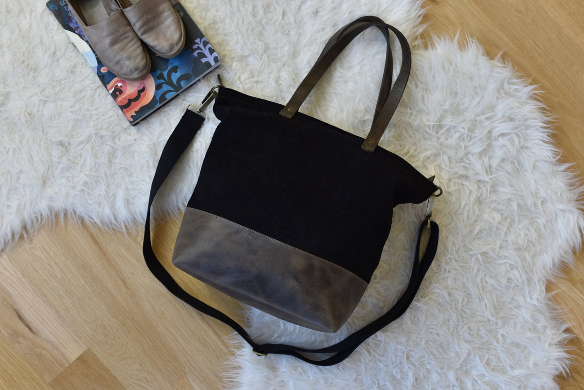 a black and grey bag on a white fur rug