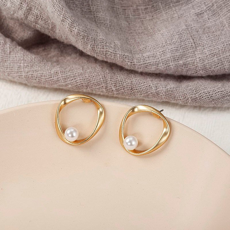 a pair of gold earrings with pearls on a plate