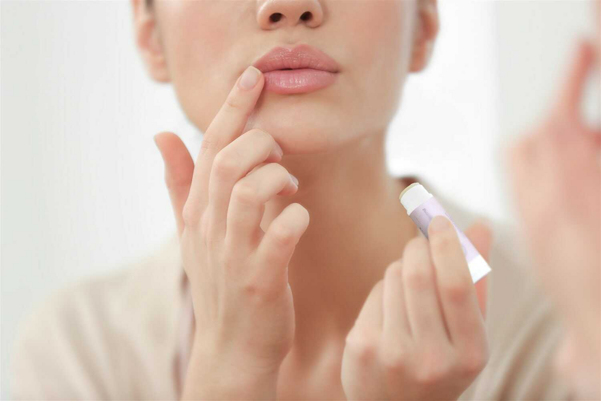 a woman applying lip balm