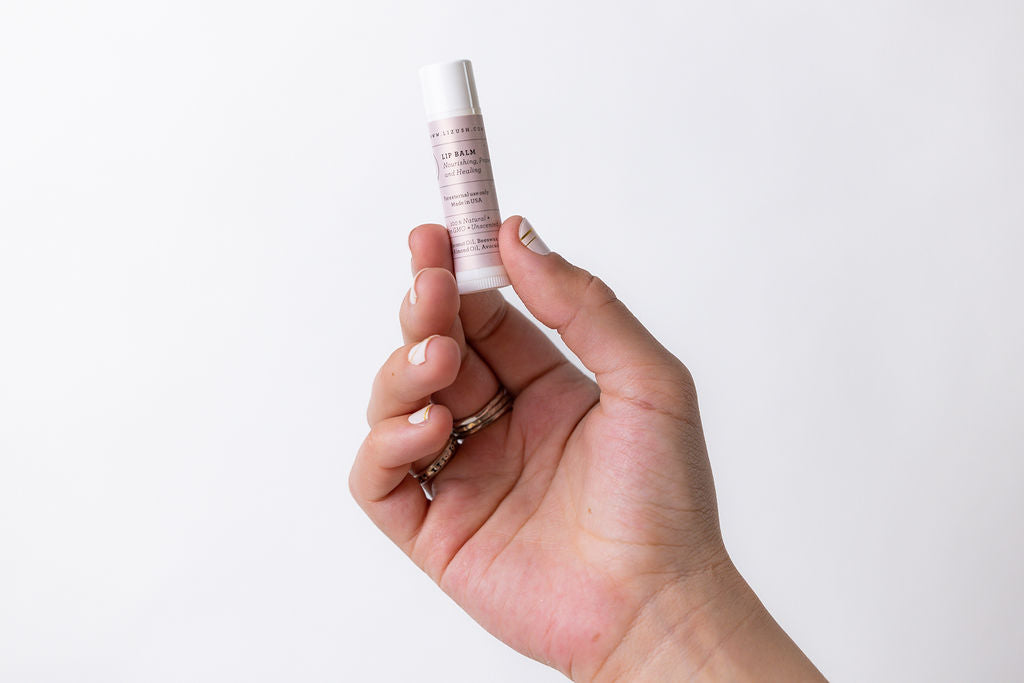 a hand holding a small tube of lip balm