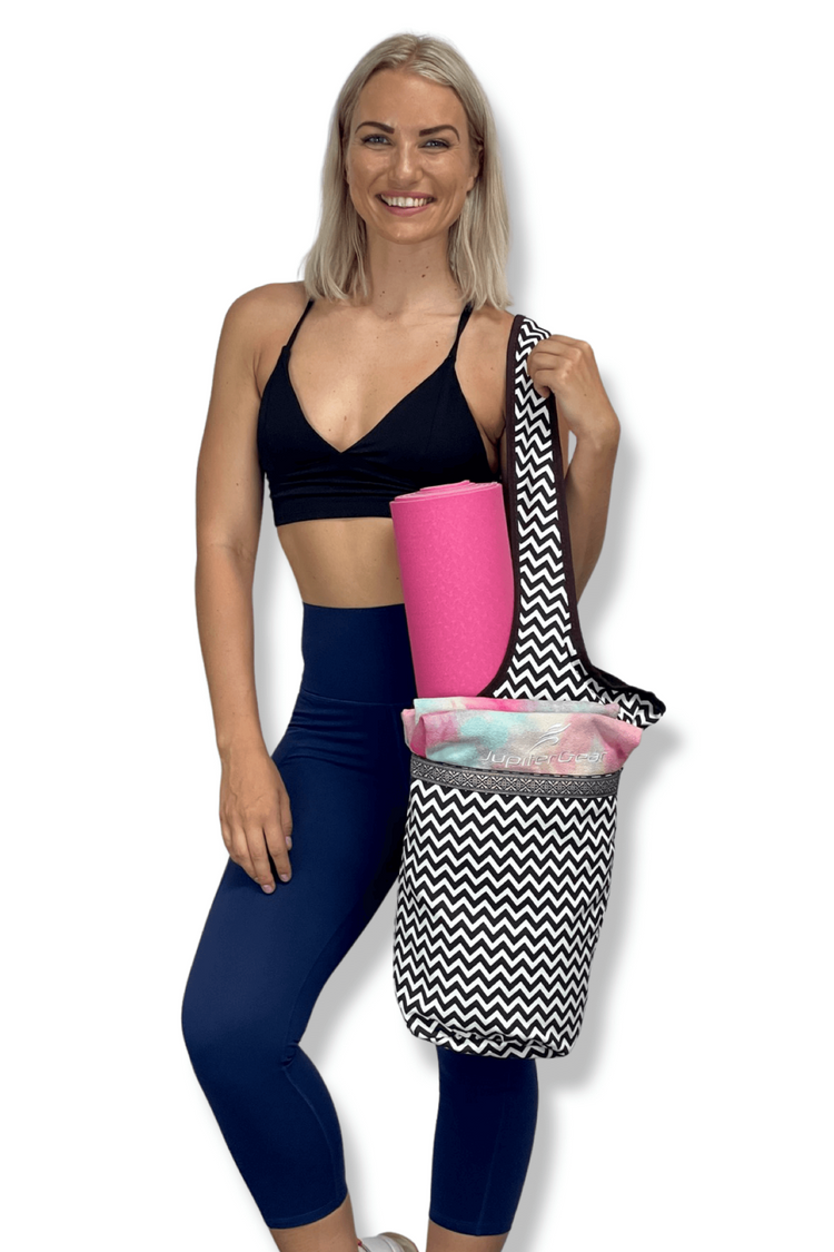 a woman holding a yoga mat and a bag