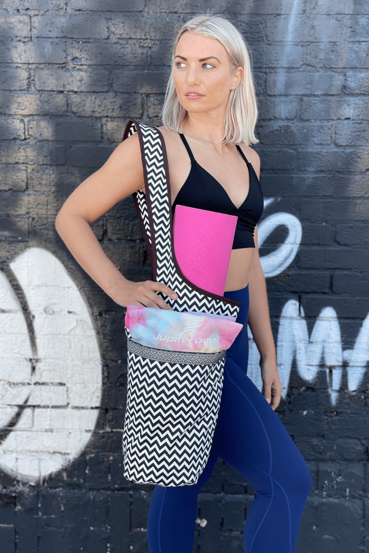 a woman in sports garment and leggings holding a yoga mat
