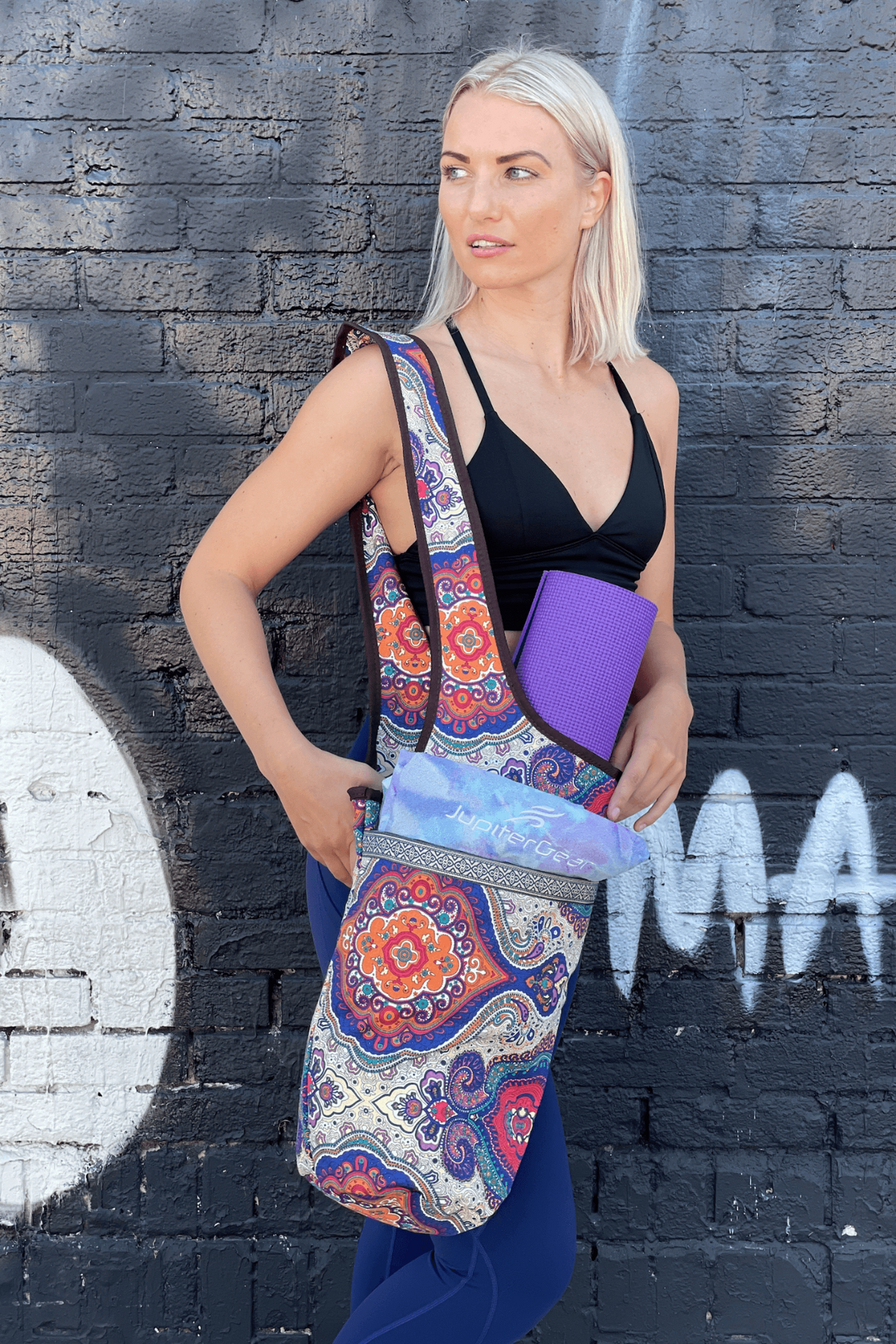 a woman in a black top and leggings holding a yoga mat
