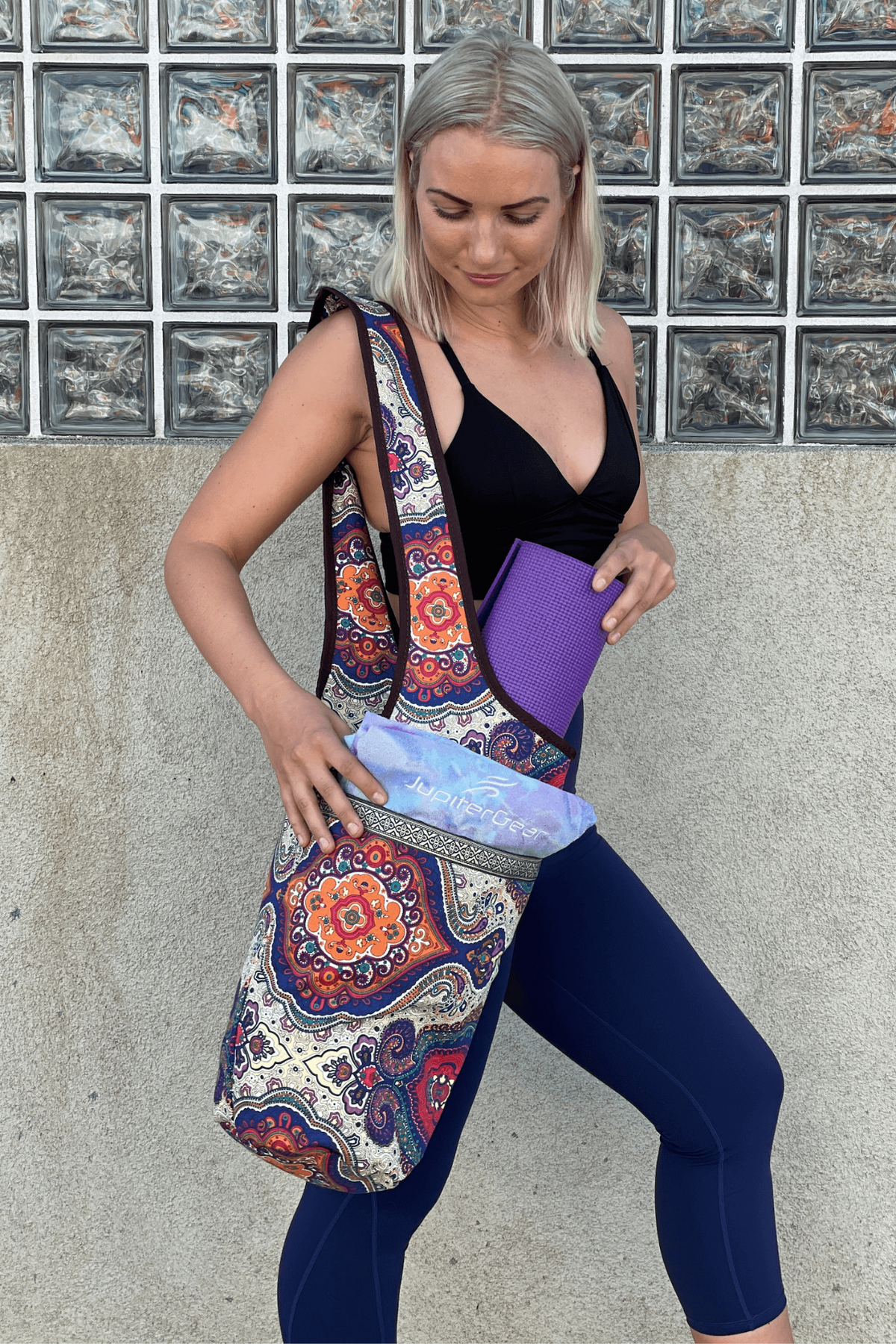 a woman holding a yoga mat and a bag