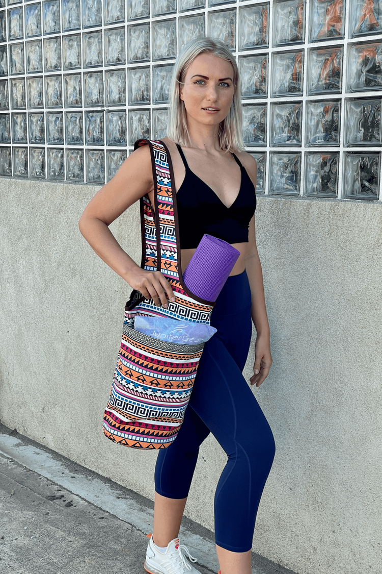 a woman in sports garment and leggings holding a yoga mat