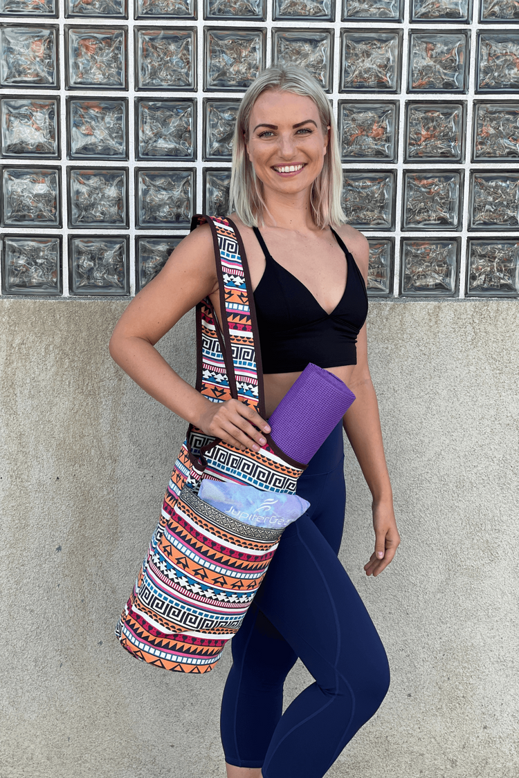 a woman in sports garment and leggings holding a yoga mat