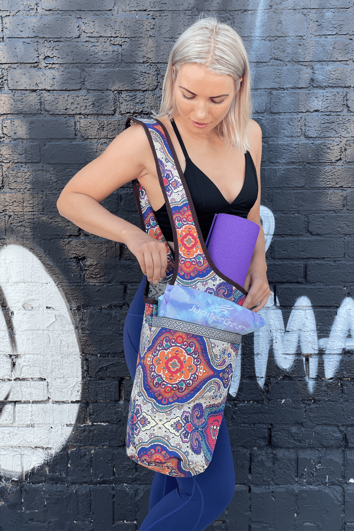 a woman holding a yoga mat in front of a wall