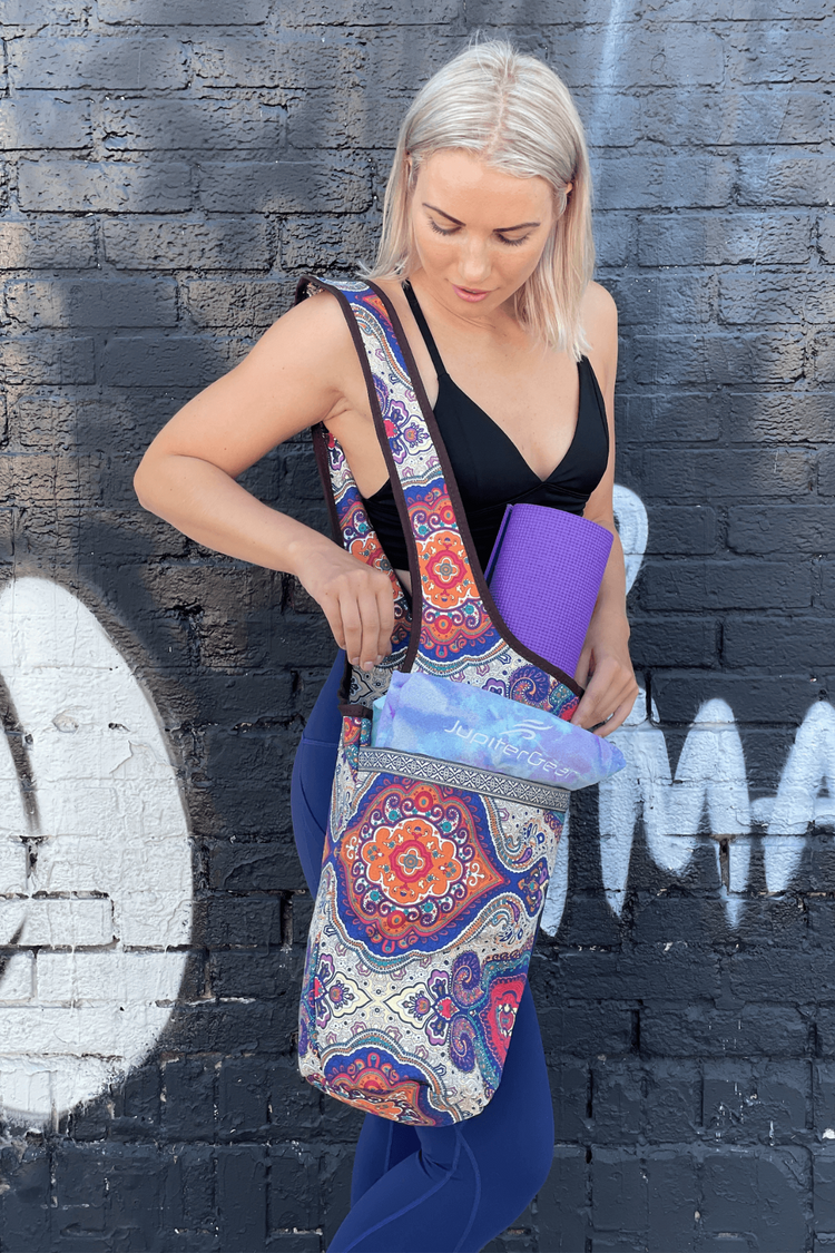 a woman holding a yoga mat in front of a wall
