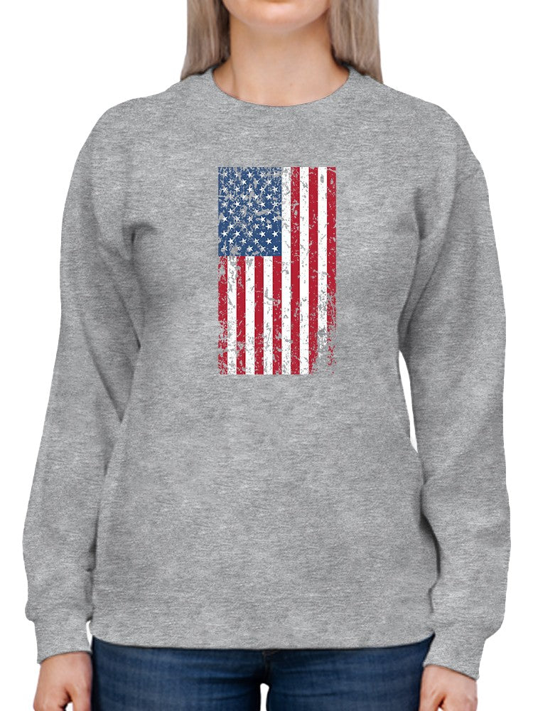 a person wearing a grey sweatshirt with a flag on it