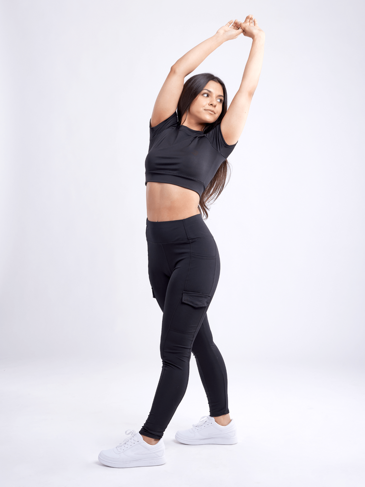 a woman in black clothes with her arms up