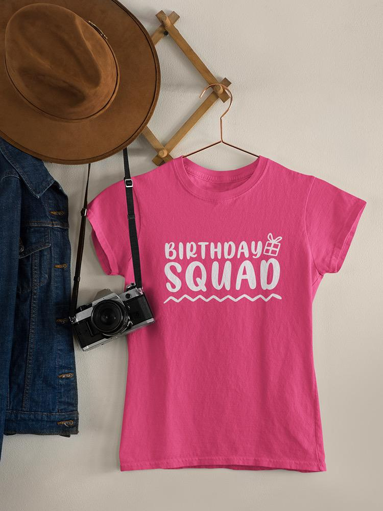 a pink shirt with a camera and a hat on a swinger