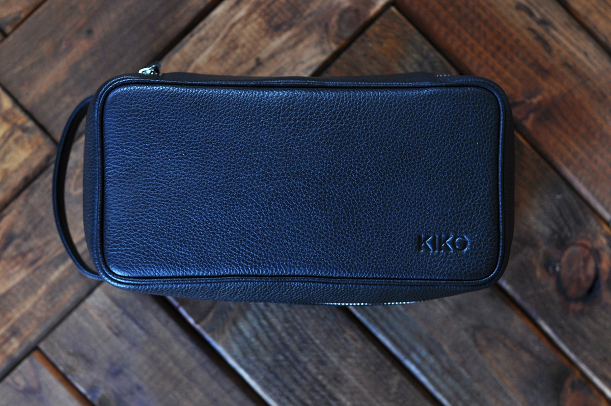 a black leather bag on a wood surface