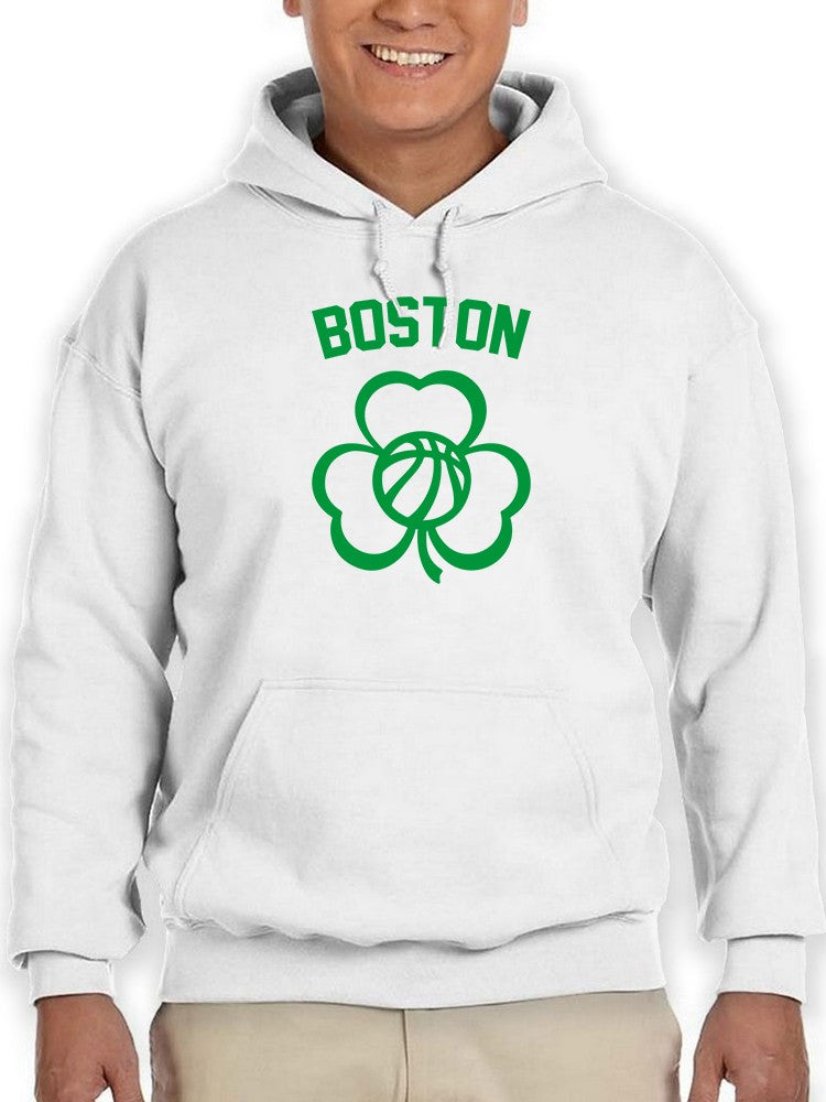a person wearing a white sweatshirt with a green clover and a ball