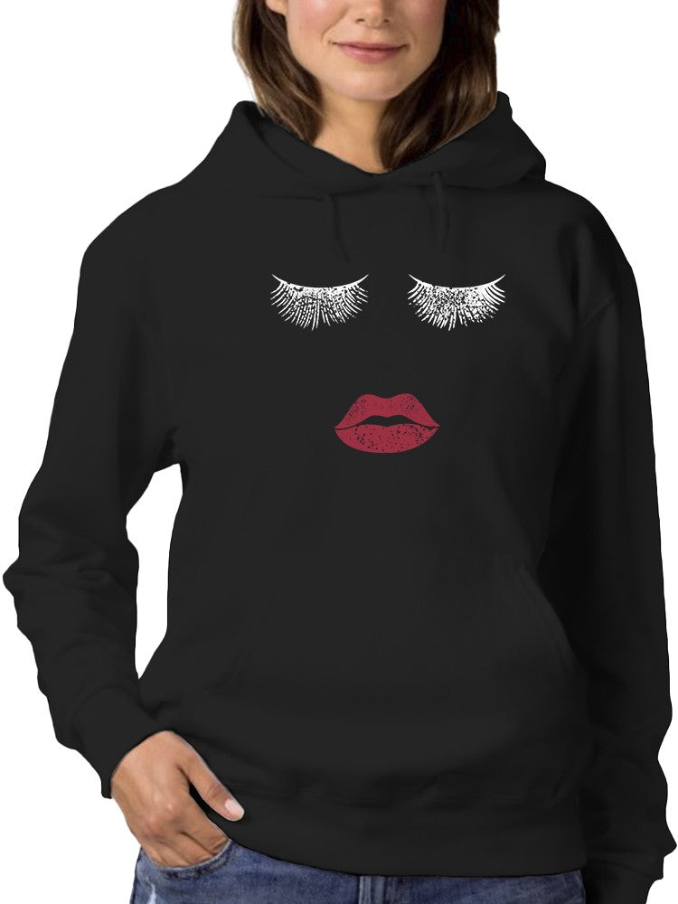 a woman wearing a black hoodie with a face and eyelashes