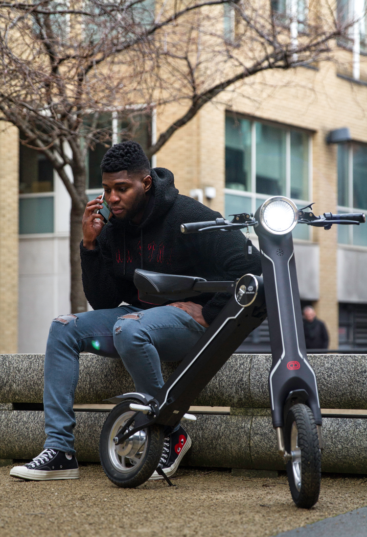 a man sitting on a bench with a scooter