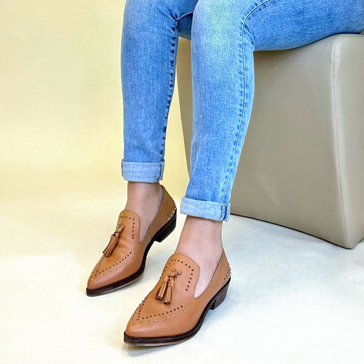 a person's legs and feet wearing blue jeans and brown shoes