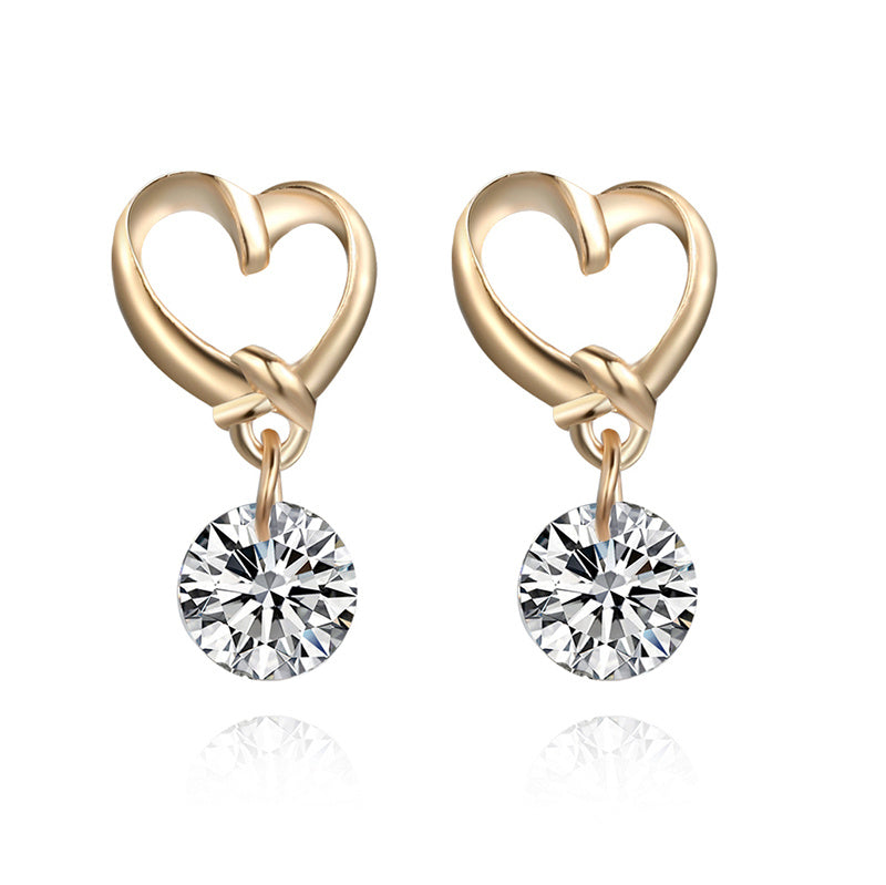 a pair of gold heart shaped earrings with a diamond