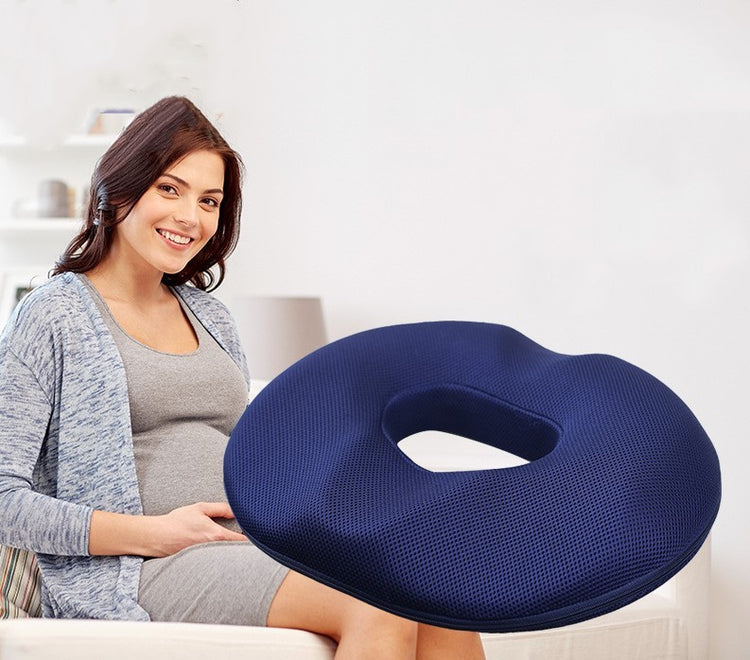 a pregnant woman sitting on a couch with a blue pillow