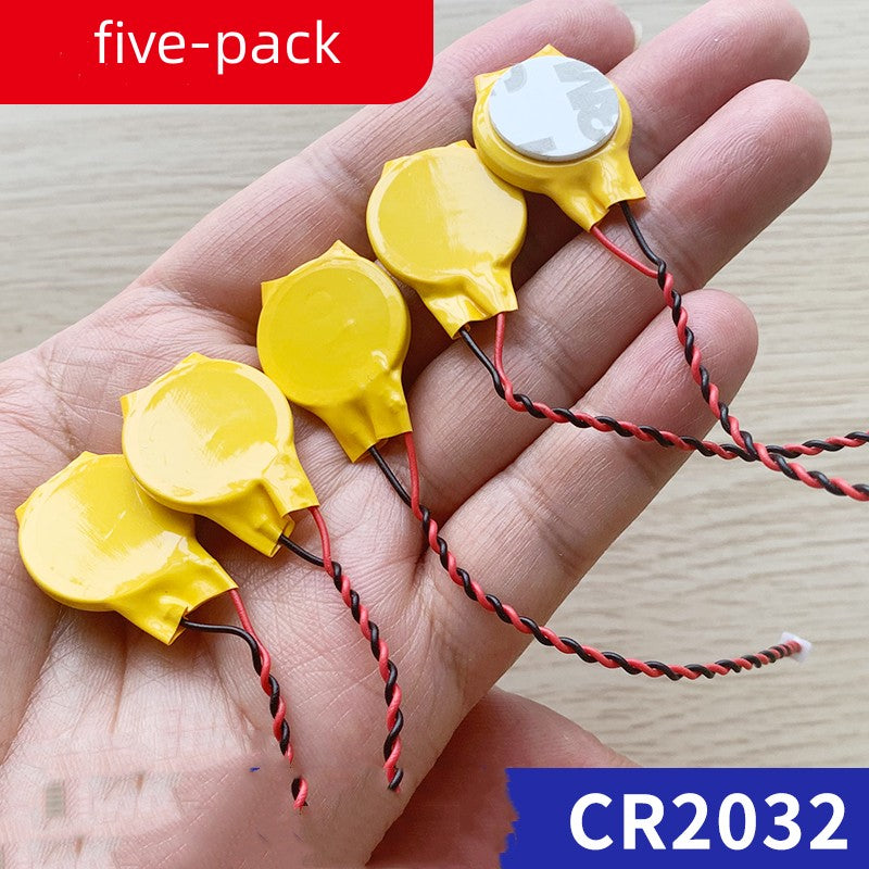 a hand holding small yellow round objects with wires