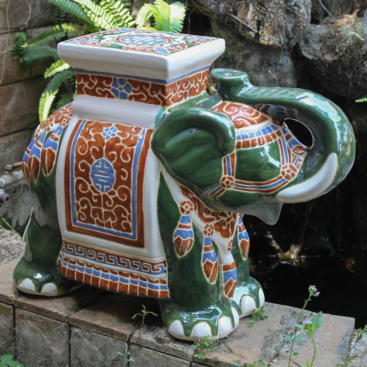 a ceramic elephant statue on a brick surface