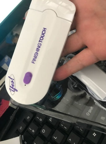 a hand holding a white device