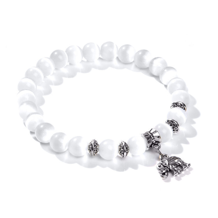 a white beaded bracelet with a silver elephant charm