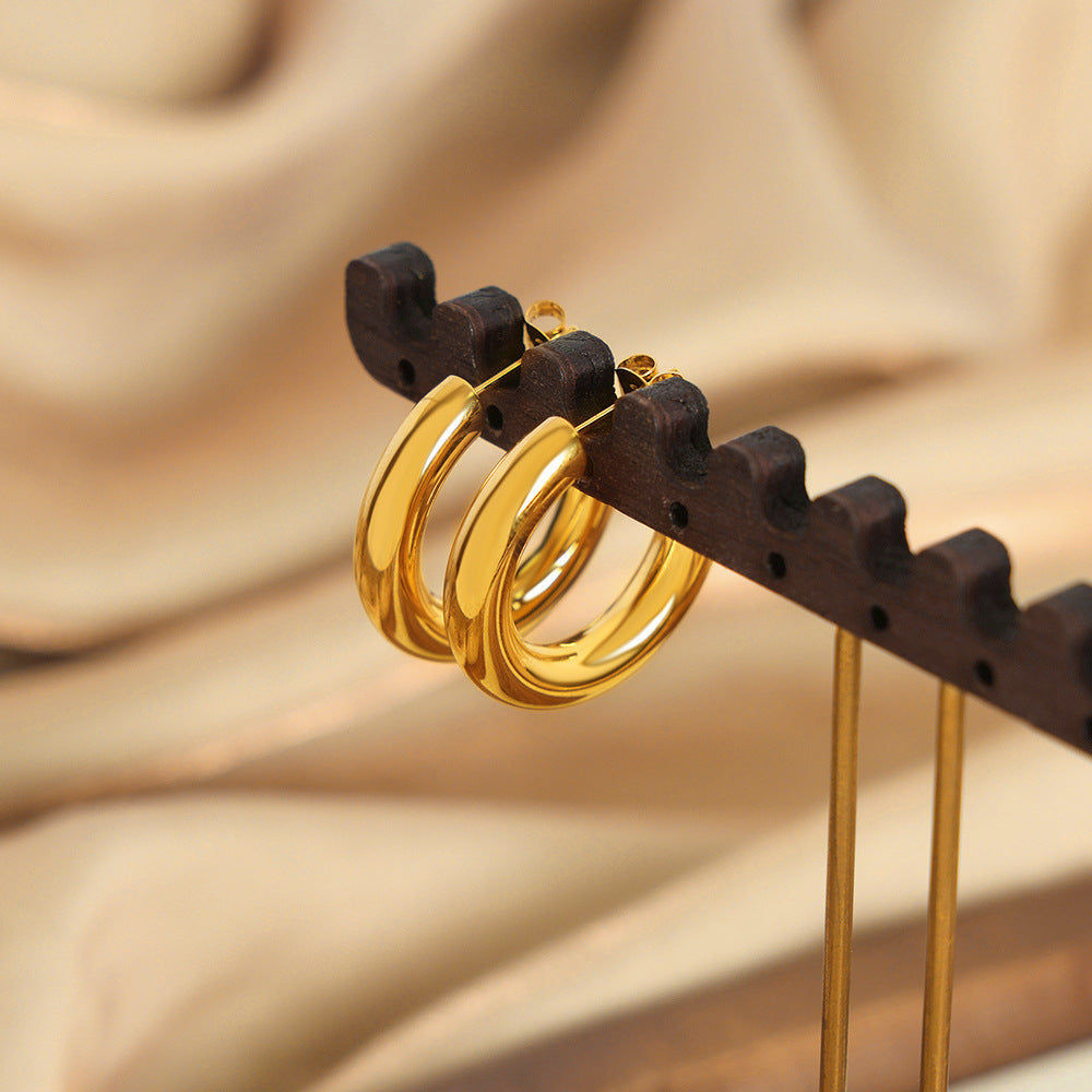 a pair of gold hoops on a wooden stand
