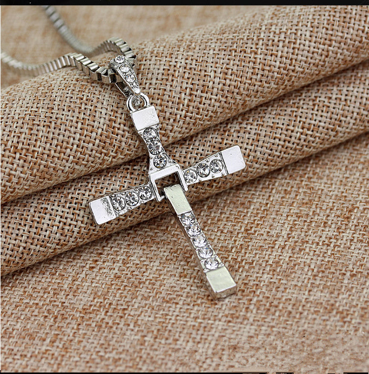 a silver cross necklace on a piece of cloth