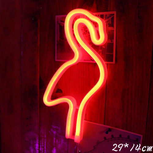 a neon flamingo sign on a wood wall