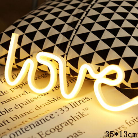 a yellow neon sign on a black and white patterned pillow