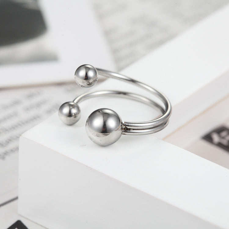 a silver ring with balls on a white box