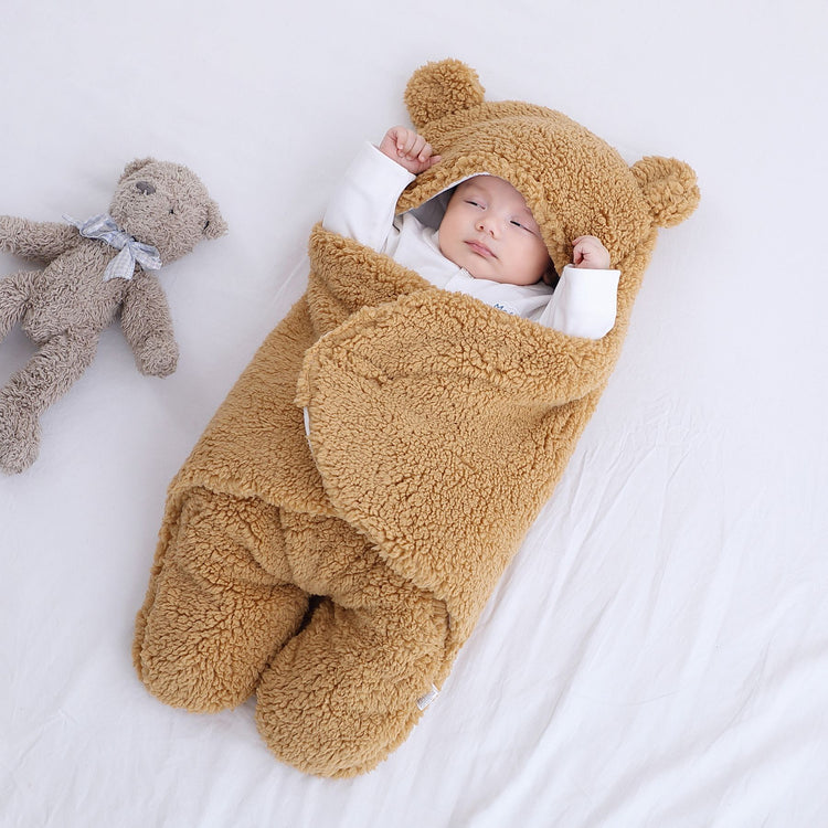 a baby lying on a blanket next to a stuffed bear