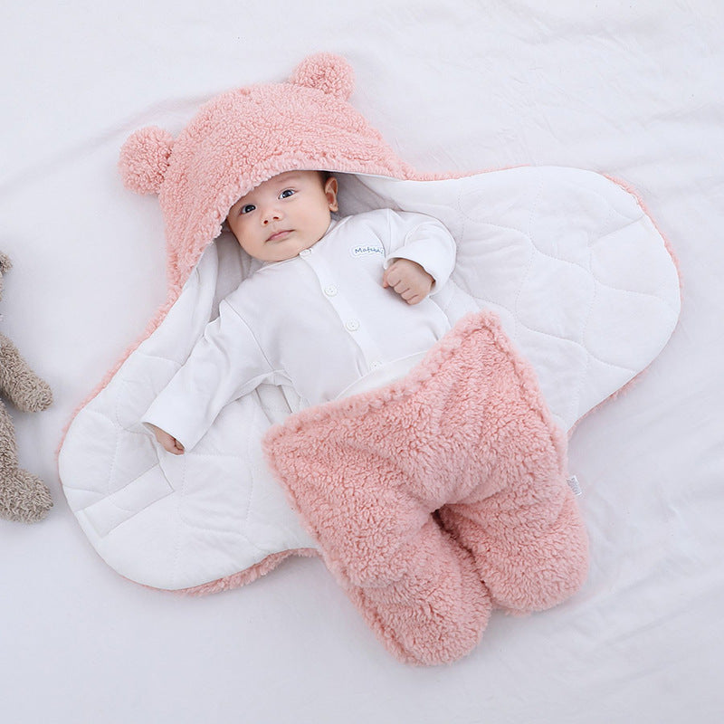 a baby lying in a blanket with a stuffed animal