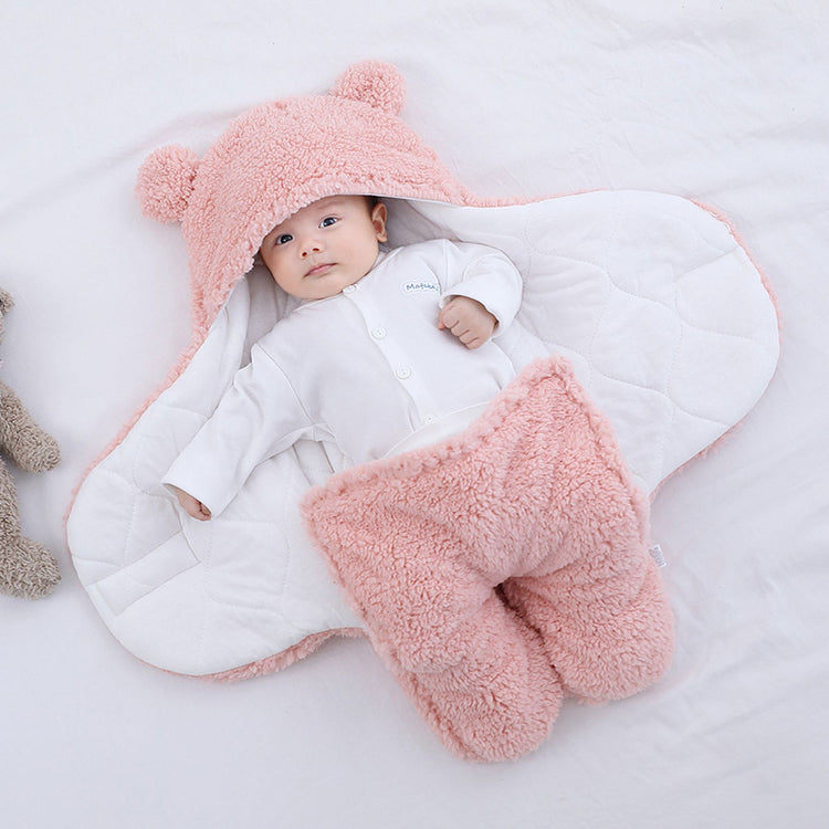 a baby lying in a blanket with a stuffed animal