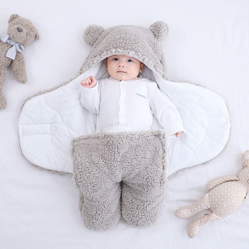 a baby lying in a blanket with a bear garment